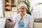 Senior woman with remote watching tv at home