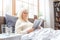 Senior woman resting at home reading book in bed elderly lifestyle