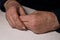 Senior woman`s folded hands lie on the table. Wrinkles on the hands.