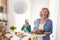 Senior woman serving roasted chicken for Thanksgiving dinner with friends