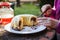 Senior woman serving slice of cake in garden