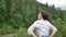 Senior woman with short dark hair doing a stretching exercise for relaxation in the morning outside over landscape of