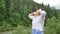 Senior woman with short dark hair doing a stretching exercise for relaxation in the morning outside over landscape of