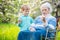 Senior woman showing something in hand to great grandson while relaxing in orchard