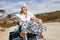 Senior woman sits on motorcycle on desert road