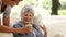 Senior Woman Sits Reading Book As Grandson Brings Hot Drink