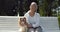 Senior woman sitting on bench with cavalier spaniel in park