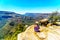 Senior woman sitting on a cliff`s edge, enjoying the view of the Blyde River Canyon from the viewpoint at the Three Rondavels