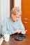 Senior woman sitting at the desk and cutting fingers nails