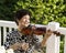 Senior woman sitting down while playing her violin outdoors