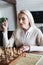 Senior woman sitting near blurred chess