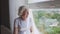 Senior woman sitting on windowsill.