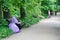 Senior woman sitting on wooden bench and reading a book in botanical garden `Aptekarsky garden` in Moscow