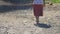 Senior woman in skirt with machete walks along dirty road