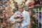 Senior woman smiling, holding bouquet of flowers in hand in flower shop