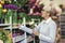 Senior woman smiling, holding bouquet of flowers in hand in flower shop