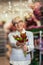 Senior woman smiling, holding bouquet of flowers in hand in flower shop