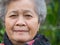 Senior woman smiling and looking at the camera while standing in a garden. Headshot photo. Concept of aged people and healthcare