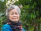 Senior woman smiling and looking at the camera while standing in a garden. Headshot photo. Concept of aged people and healthcare