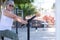 Senior woman in sporty activity in public park, sitting on bicycle equipment  doing exercises, smiling