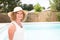 Senior woman standing outside her pool and house Content woman smiling and looking at camera