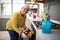 Senior woman taking tray of fresh cookies out of oven in kitchen