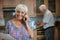 Senior woman talking on mobile phone while man working in kitchen