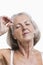 Senior woman tweezing eyebrows against white background