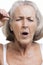 Senior woman tweezing eyebrows against white background