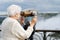 Senior woman using binoculars at niagara falls