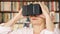 Senior woman using VR 360 glasses at home. Active modern elderly people. Bookshelves in background