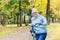 Senior woman walking in the park with a bicycle, sunny day