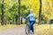 Senior woman walking in the park with a bicycle, sunny day