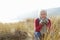 Senior Woman Walking Through Sand Dunes On Winter Beach