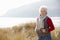 Senior Woman Walking Through Sand Dunes On Winter Beach