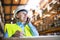 Senior woman warehouse manager or supervisor with smartphone, making phone call.
