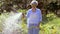 Senior woman watering lawn by hose at garden