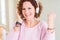 Senior woman wearing headphones listening to music screaming proud and celebrating victory and success very excited, cheering