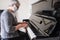 A senior woman wearing a protective face mask while playing the piano at home