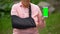 Senior woman wearing shoulder immobilizing sling showing smartphone green screen