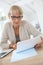 Senior woman wearing trendy eyeglasses making paperwork