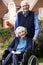 Senior Woman In Wheelchair Being Pushed By Husband