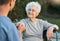 Senior woman, wheelchair and caregiver holding hands with patient for empathy, support and care outdoor for