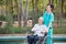 Senior woman on wheelchair with nurse in nursing home hospital garden