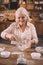 Senior woman whipping cream with whisk in glass bowl