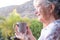 Senior woman at the window holding a cup of coffee. Smiling elderly grey haired looking away