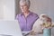 Senior woman working on laptop at home or uses some online services or buys something