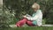 Senior woman writes in notebook sitting on grass