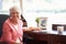 Senior Woman Writing Memoirs In Book At Desk