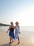 Senior women walking barefoot at beach line at sunset. Vertical photo